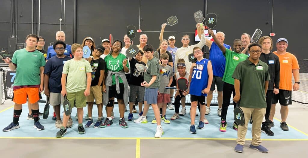 Group of students and adults holding pickleball paddles during a Vanguard Prep School extracurricular program.