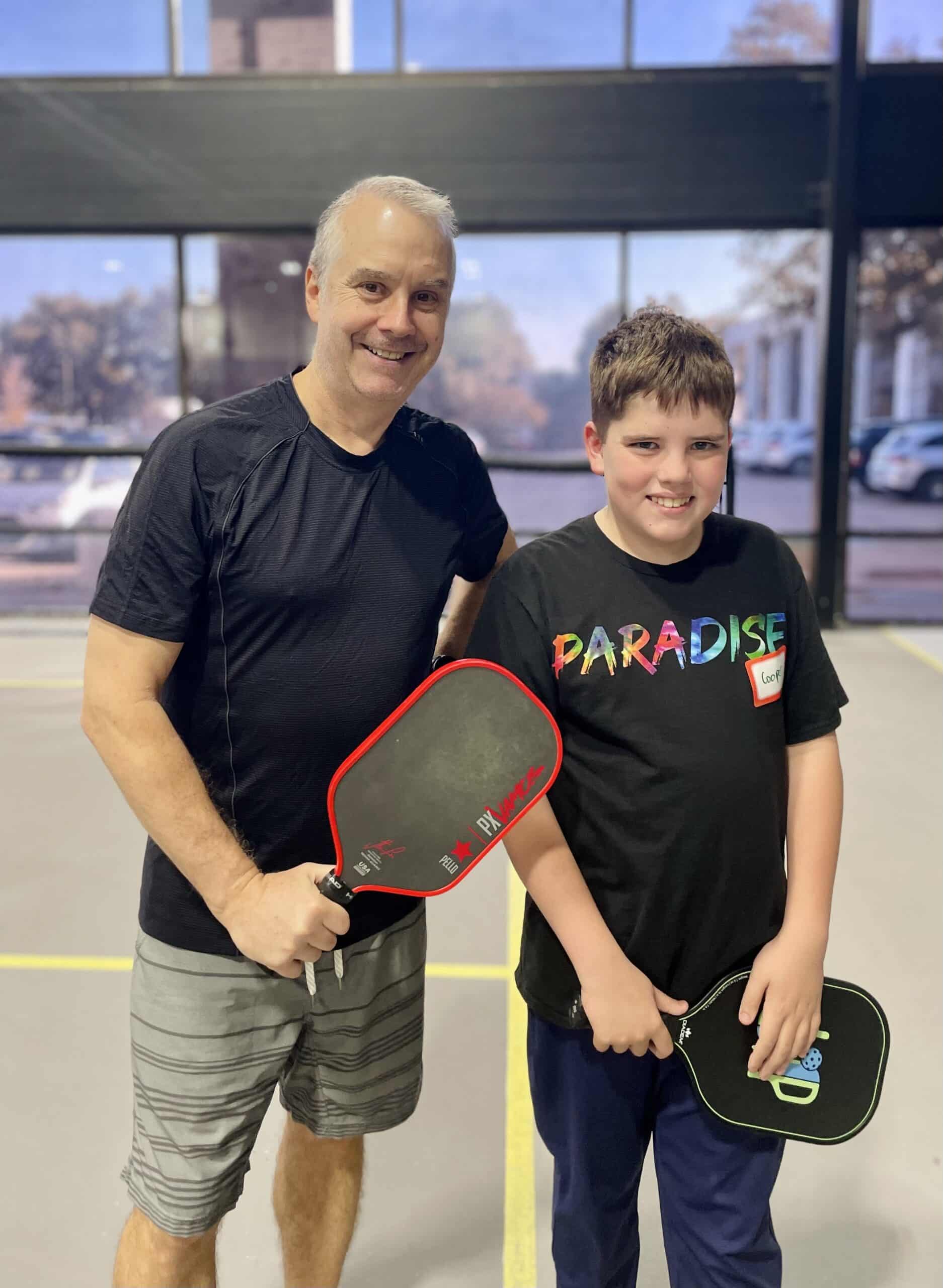 Pickleball coach and student of Vanguard posing for a photo with their paddles